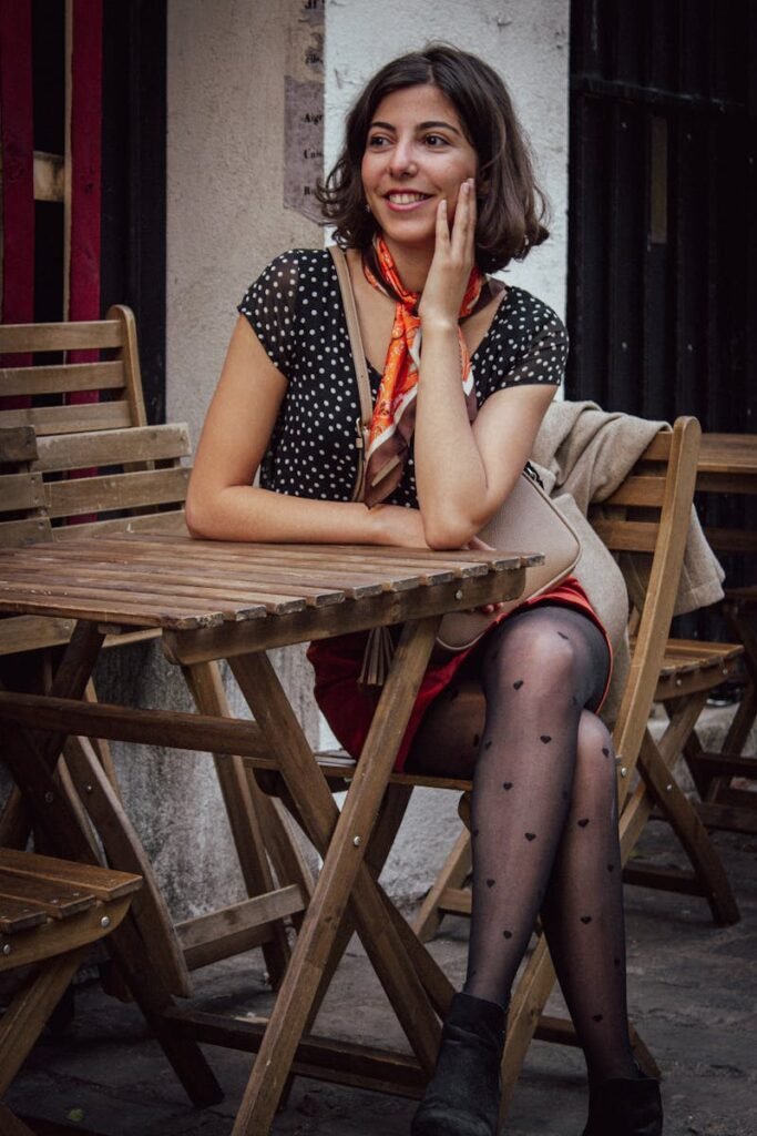 Stylish woman sits at a Paris café, exuding fashion and joy. 