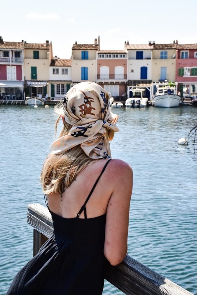 A woman with a scarf looks over the waterfront in the charming village of Port Grimaud, France.