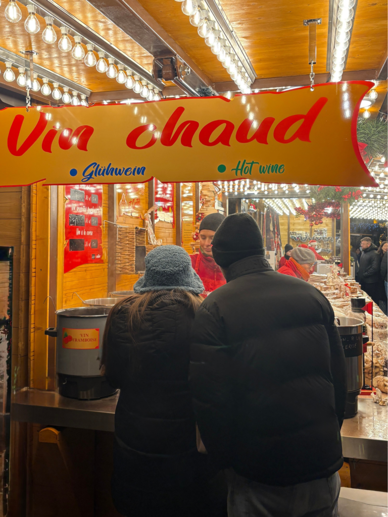 Two people at a vin chaud market stand