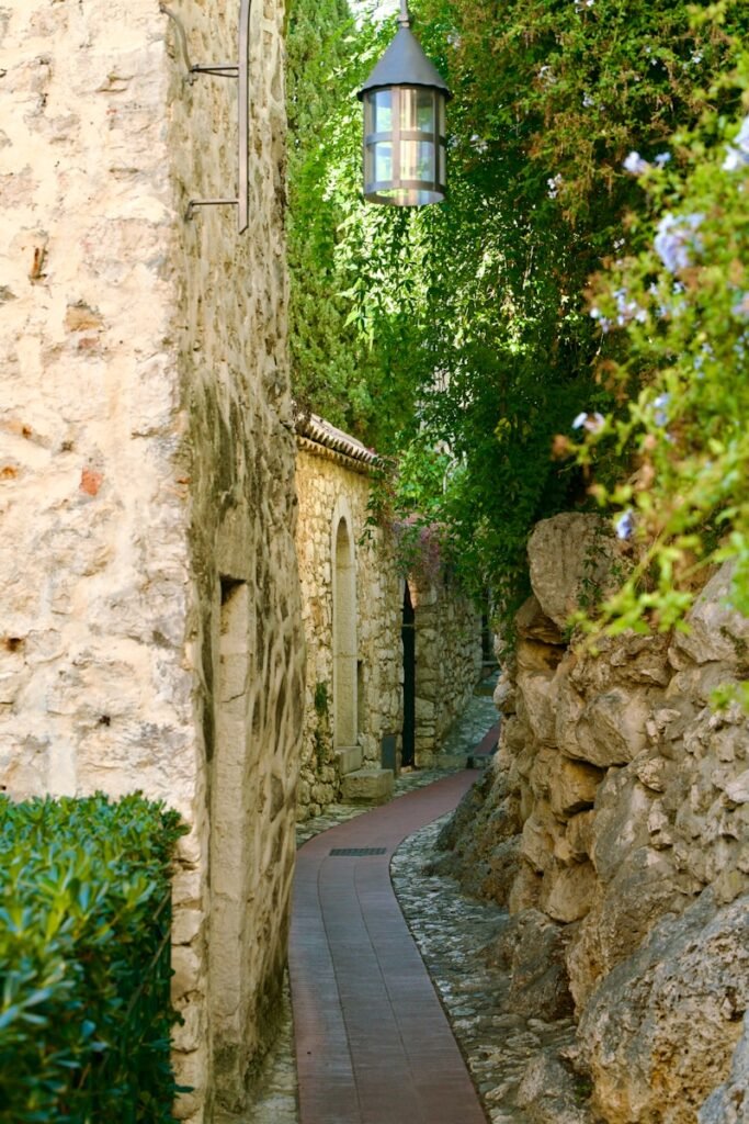 Narrow cobblestone alleyway with stone walls and greenery