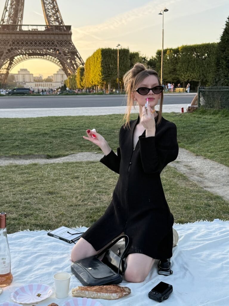 Woman enjoying a Parisian picnic near Eiffel Tower at sunset, redefining elegance.