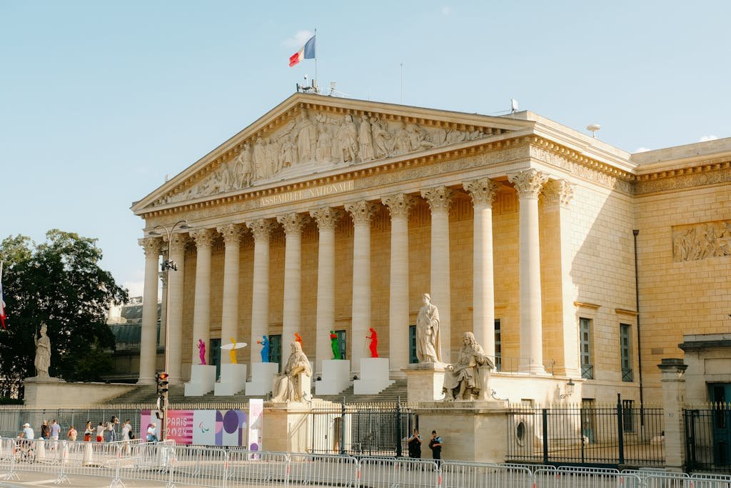 Front view of the Palais Bourbon in Paris, featuring statues and French flag.