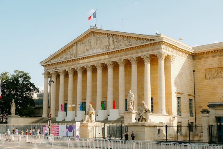 Front view of the Palais Bourbon in Paris, featuring statues and French flag.