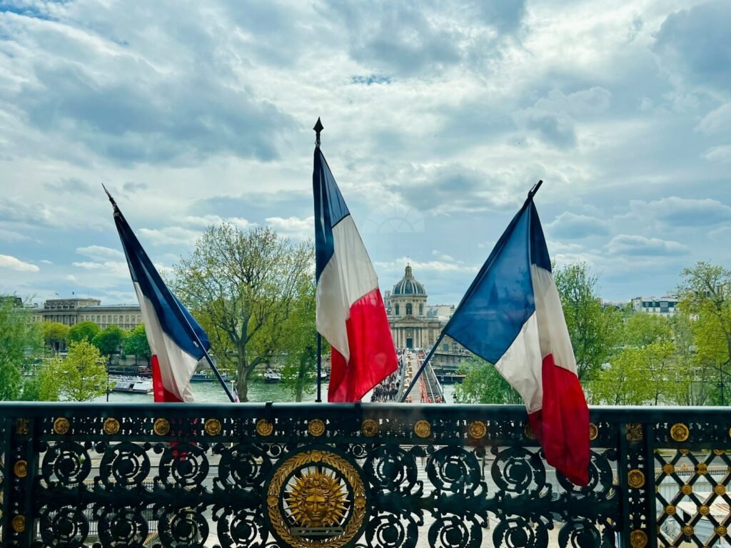 a fence with three French flags on top of it